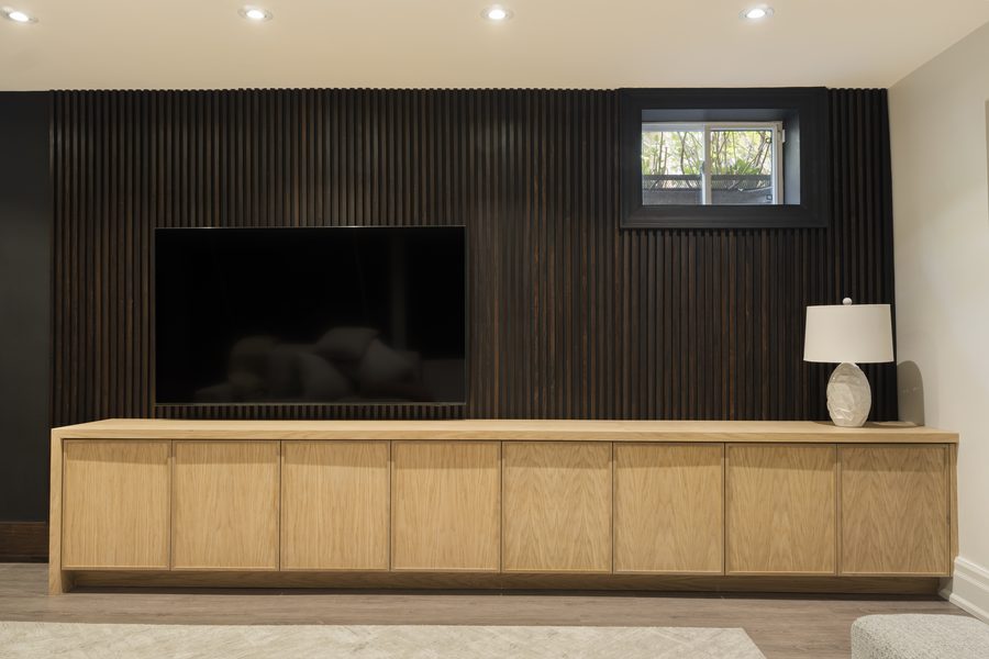 Custom TV cabinet and media wall with wood slat paneling by Pro-Con Construction