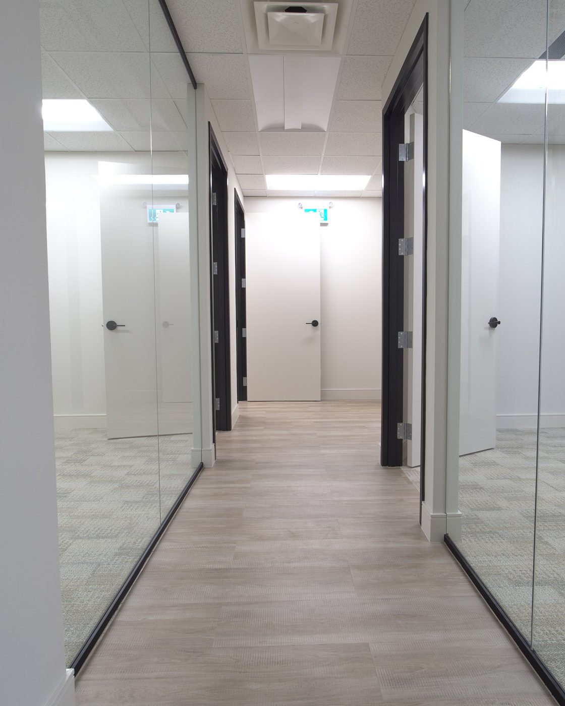 Glass-walled office corridor with commercial-grade flooring — office fit-out by Pro-Con Construction, Toronto